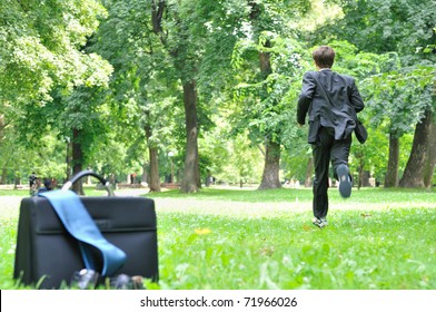 Escape From Civilization Concept - Business Man Running In Park Away From Bag, Shoes And Tie