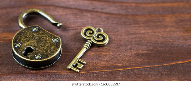 Escape room game concept, vintage golden key and opened padlock, web banner with copy space