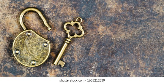 Escape room game concept. Web banner of a vintage golden key and unlocked padlock on a rusty metal background.
