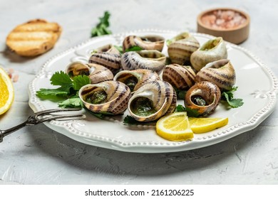 Escargots de Bourgogne Snails with herbs, butter, garlic, glass of white wine on a light background, gourmet food. Restaurant menu, Traditional French cuisine,