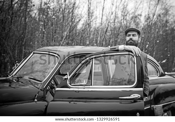 Escort man or\
security guard. Bearded man in car. Call boy in vintage auto. Retro\
collection car and auto repair by mechanic driver. Travel and\
business trip or hitch\
hiking.
