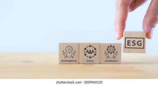 ESG concept of environmental, social and governance. Sustainable and ethical business.Businessman holds wooden cube with text "ESG" surrounding with ESG icon on beautiful white background. Copy space - Shutterstock ID 2039969135