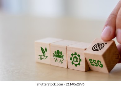 ESG concept of environmental, social and governance. Sustainable corporation development. Hand flips wooden cubes with target setting  to ESG icon with other ESG icons on bright background.Copy space.
