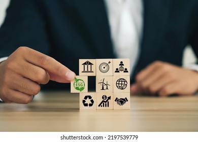 ESG concept of environmental, social, and governance. Sustainable corporation development.Businessman Hand holding Wooden blocks with ESG icons standing with other ESG icons.Net Zero. - Shutterstock ID 2197539779