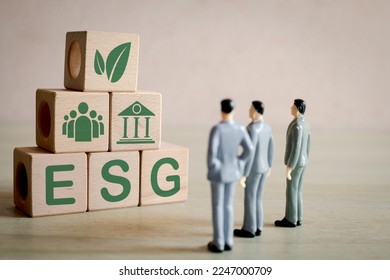 ESG ,environmental, social, and corporate governance concept.,A group of business man focus on wooden cubes with ESG word and icon showcasing a commitment to ethical and sustainable business.