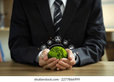 ESG environmental social governance business strategy investing concept. Businessman holding green world ball with Esg icons.Ethical and sustainable investing. Enhance ESG alignment of investments.
