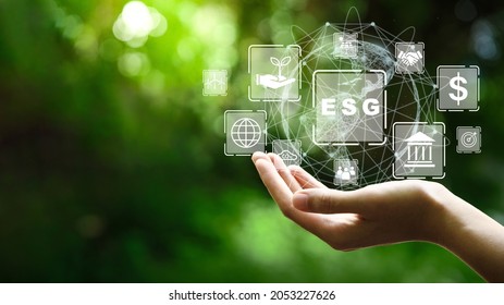 ESG icon concept in the hand for environmental, social, and governance in sustainable and ethical business on the Network connection on a green background. - Shutterstock ID 2053227626