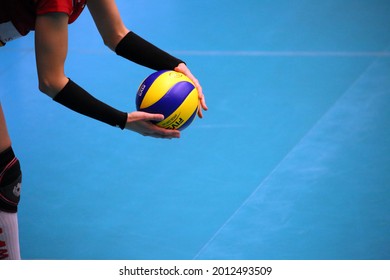 Eskisehir, Turkey - 07.20.2021: A volleyball player woman holding a blue and yellow volleyball ball with both hands next to her on a blue background