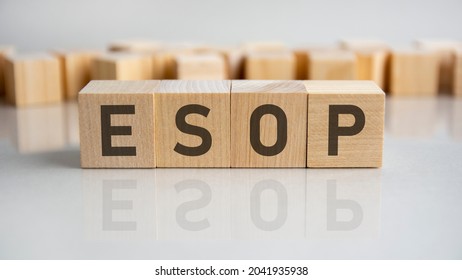 esop - employee stock ownership plan - word of wooden blocks with letters on a gray background. Reflection of the caption on the mirrored surface of the table. Selective focus.