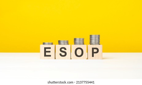 esop - letters on wooden blocks in yellow background with increasing stack of coins, growing trend, business concept. ESOP - short for Employee Stock Ownership Plan