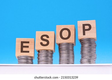 esop - text on wood blocks stack with coins, blue background, business concept. esop - Employee Stock Ownership Plan