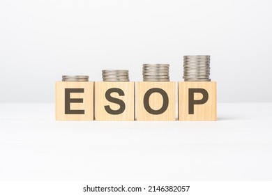 esop text written on wooden block with stacked coins on white background, business concept. esop - short for Employee Stock Ownership Plan