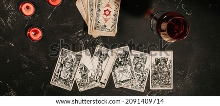 Esoteric magic composition top view with Tarot cards laying face up and deck on red background with burning candles and glass of red wine, magic, occult and forecasting concept