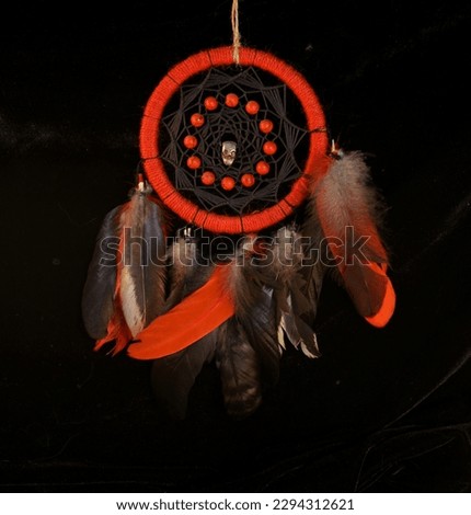 Esoteric and occult still life with red dreamcatcher against black background. Halloween, mystic and gothic concept