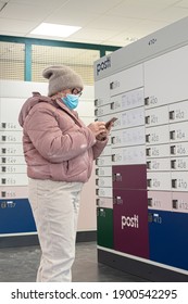 Espoo, Finland January 9, 2021 Post Office Woman Picks Up A Parcel. She Is In A Medical Mask, Looks At The Code On The Phone, She Is In A Contactless Office.