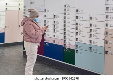 Espoo, Finland January 9, 2021 Post Office Woman Picks Up A Parcel. She Is In A Medical Mask, Looks At The Code On The Phone, She Is In A Contactless Office.