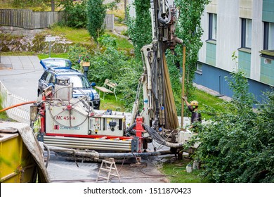 Espoo, FINLAND - JULY 5, 2019: Geothermal Heat Pump Installation In Eco Friendly Apartment House. Drilling Rig In Yard. Worker In Hard Hat Drilling A Borehole For Geothermal Heating System.  