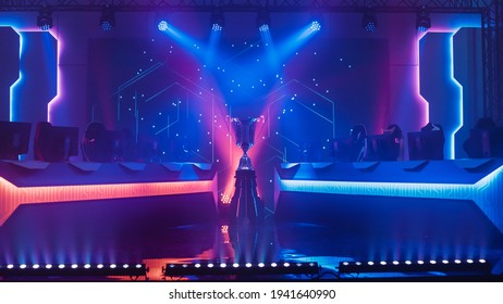 ESports Winner Trophy Standing On A Stage In The Middle Of The Computer Video Games Championship Arena. Two Rows Of PC For Competing Teams. Stylish Neon Lights With Cool Area Design.