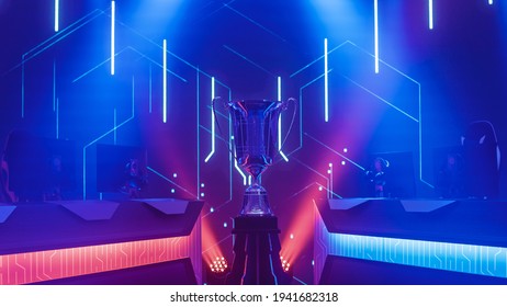 eSports Winner Trophy Standing on a Stage in the Middle of the Computer Video Games Championship Arena. Two Rows of PC for Competing Teams. Stylish Neon Lights with Cool Design. - Shutterstock ID 1941682318