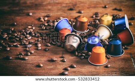 Espresso coffee capsules, pods and coffee beans on wooden background
