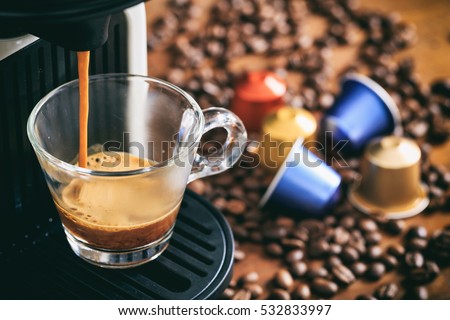 Espresso coffee maker and capsules on a wooden table