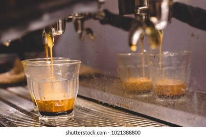 Espresso Coffee Shot Pouring Into Piccolo Clear Grass From A Espresso Machine In Cafe. Close-up