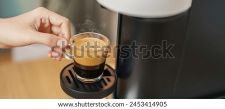 Espresso cup with steam and froth during Coffee making Coffee by Coffee Maker Machine on wood table bar. Cafe shop, Daily beverage drink at Home, Apartment and Office concept