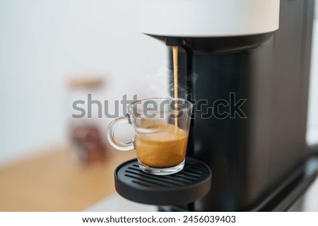 Espresso cup with steam and froth during Coffee making Coffee by Coffee Maker Machine on wood table bar. Cafe shop, Daily beverage drink at Home, Apartment and Office concept