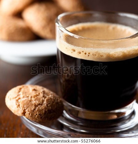 Espresso. Glass of coffee with a sweet cookie. Symbolic image. Rustick wooden background. Close up. 