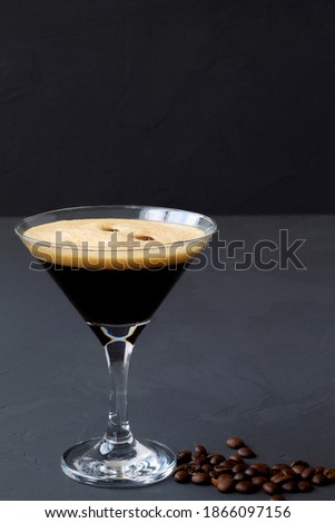 Espresso Martini cocktails garnished with coffee beans on table. Martini glass on a black background. vertical. alcohol drinks