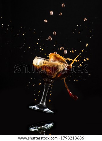 Espresso Martini drink in floating glass with splashing foam and falling coffee beans