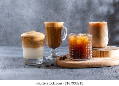 Espresso Tonic, cold drink with espresso and tonic in glass. Ice coffee in a tall glass with cream poured over and coffee beans. Set with different types of coffee drinks on a dark table.
