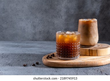 Espresso Tonic, cold drink with espresso and tonic in glass. Ice coffee in a tall glass with cream poured over and coffee beans. Set with different types of coffee drinks on a dark table.