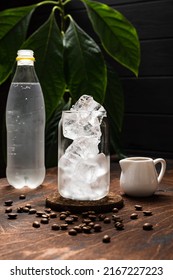 Espresso Tonic In The Making. A Highball Glass Filled With Ice Cubes, Tonic Soda Water, Coffee Beans, Milk Jug, Wooden Background