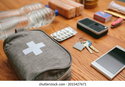 Essential Items Prepared For Emergency Backpack. Selective Focus On First Aid Kit In The Foreground