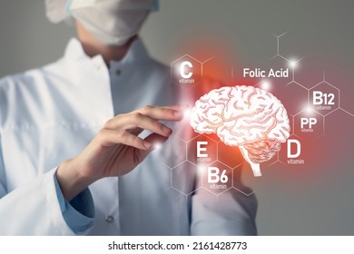 Essential Nutrients For Brain Health Including Vitamin C, Vitamin B, Folic Acid, Vitamin PP. Blurred Portrait Of Doctor Holding Highlighted Brain.