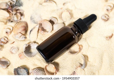 Essential Oil Bottle On A Sandy Beach With Shells. Aroma Oil Bottle On A Summer Beach. Summer Vacation Essential Oil