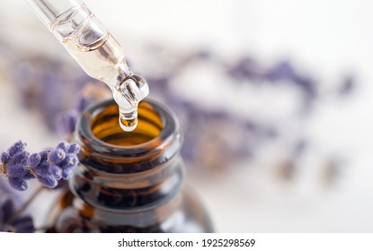 Essential oil with a dropper pipette and lavender branches on a white background with copy space. Brown glass cosmetic bottle, serum.