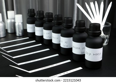 essential oil and frangrance oil bottle on black wooden table with blotter paper for testing smell during blending process for choosing nice scent for making scented candles and body perfume in lab