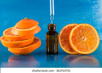 Essential oil with orange slices, bottle and dropper, with blue background (horizontal)