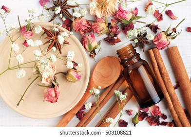 Essential oil of rose, cinnamon, anise mix. Herbal aroma beauty care. Dropper bottle, dried fragrant flowers, sticks, wooden utensils, top view background.