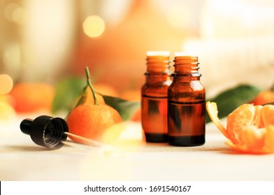 Essential oil of tangerine for relaxing aromatherapy & beauty treatment, dropper bottles, citrus fruit, soft candle evening lights. Comfy home atmosphere, golden sparkling bokeh