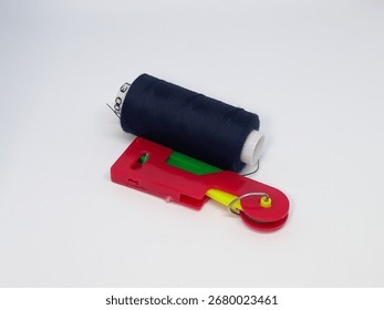 Essential sewing tools, a spool of dark thread and a vibrant cutter, stand ready for your next creative project on a clean white background