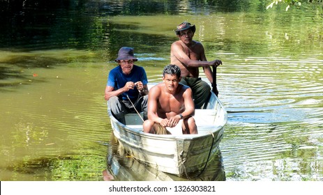 Essequibo River / Guyana - November 27 2013: Three Indigenous Men Rowing Canoe Through Calm Green River In Guyana Jungle.