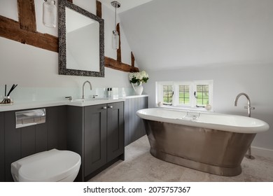 Essex, England - January 18 2019: Traditional Bathroom Space With Metal Roll Edge Bath, Exposed Timber Beams And Small Leaded Window