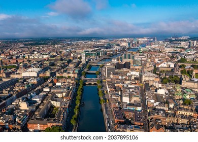 Establisher shot of Dublin skyline with river flowing with bridge connecting two sides of street surrounded by buildings during a cloudy day