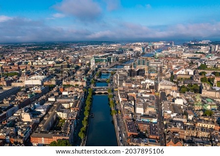 Establisher shot of Dublin skyline with river flowing with bridge connecting two sides of street surrounded by buildings during a cloudy day