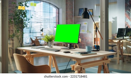 Establishing Shot: Desktop Computer Monitor with Green Screen Mock Up Chroma Key Display Standing on a Desk in Modern Creative Office. Cozy Agency Space in Loft Building. - Powered by Shutterstock