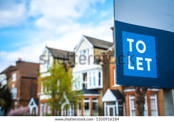 Estate agency \'To Let\' sign board with large\
typical British houses in the\
background
