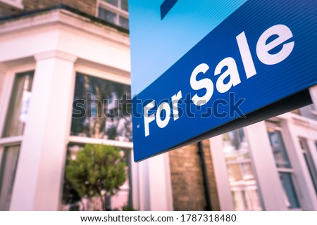 Estate agent For Sale sign on street of houses